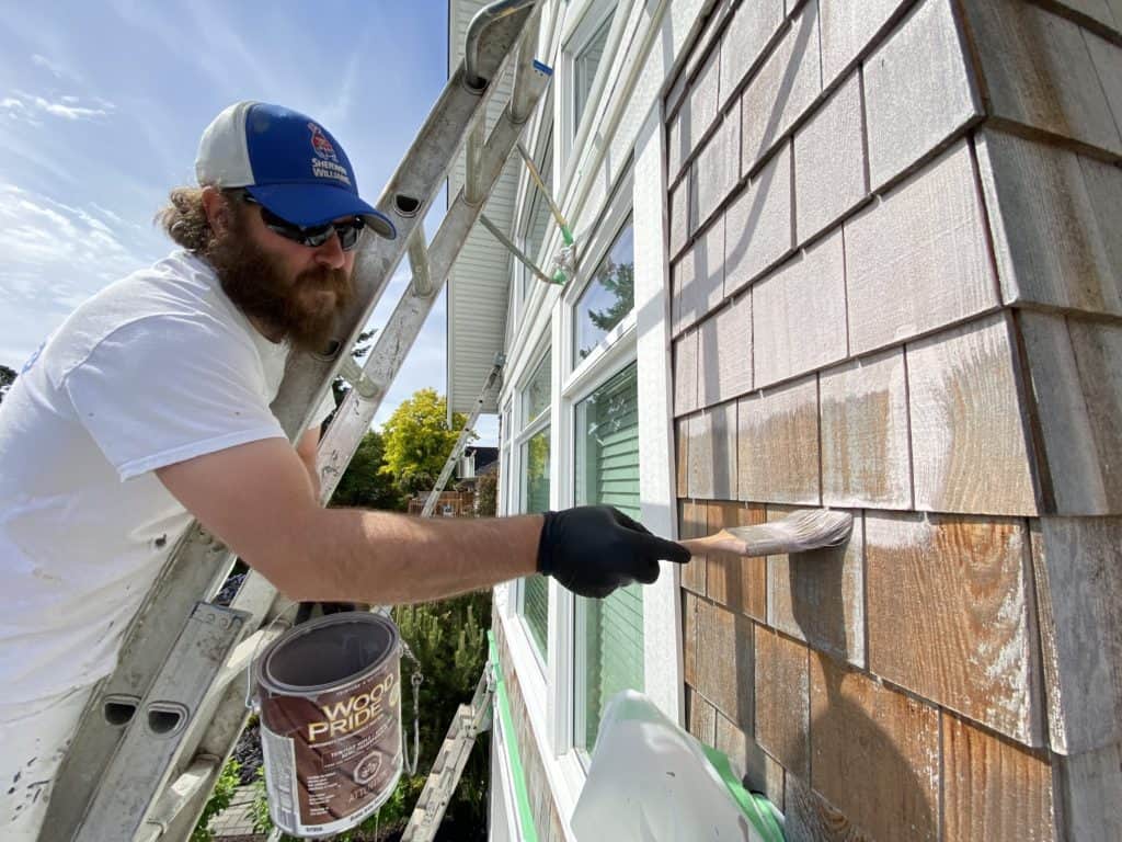 professional house painter coating shingles