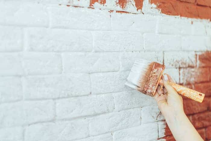 hand with brush painting brick wall