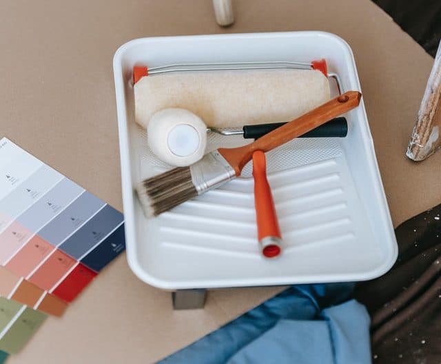 paint roller and paint brush in a paint tray