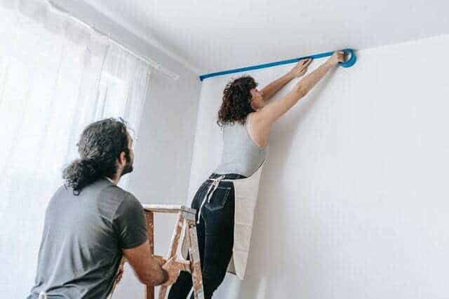 a woman cutting in her ceiling before she begins to paint