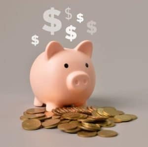 pink piggy bank with coins in front of its