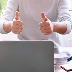 Man's hands with thumbs up in front of laptop
