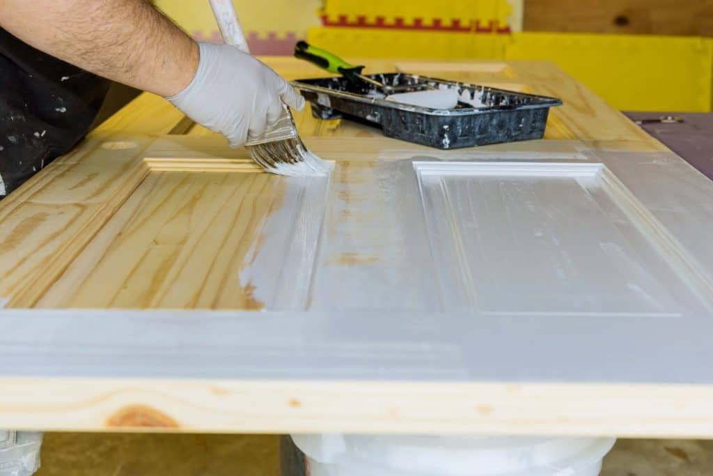 A contractor painting a wooden door