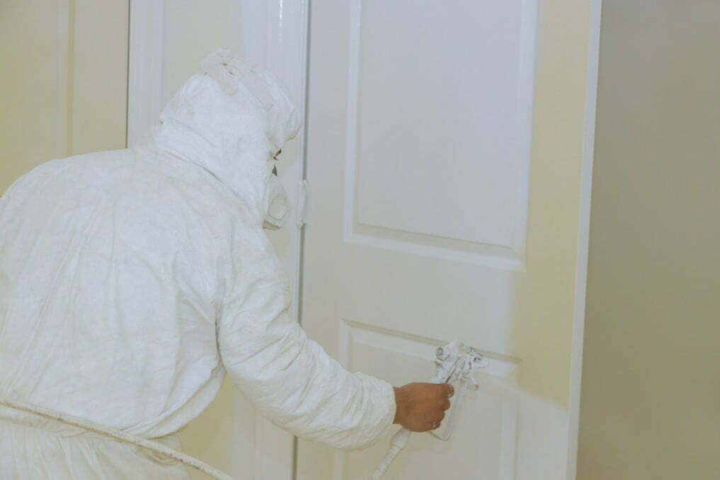 A man spray paint an interior door 