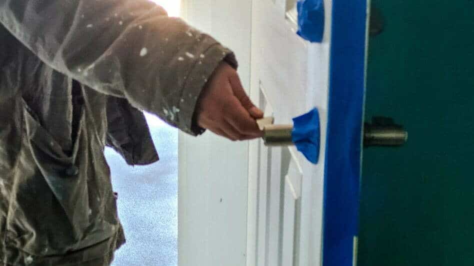A painter taping off parts of the door not to be painted